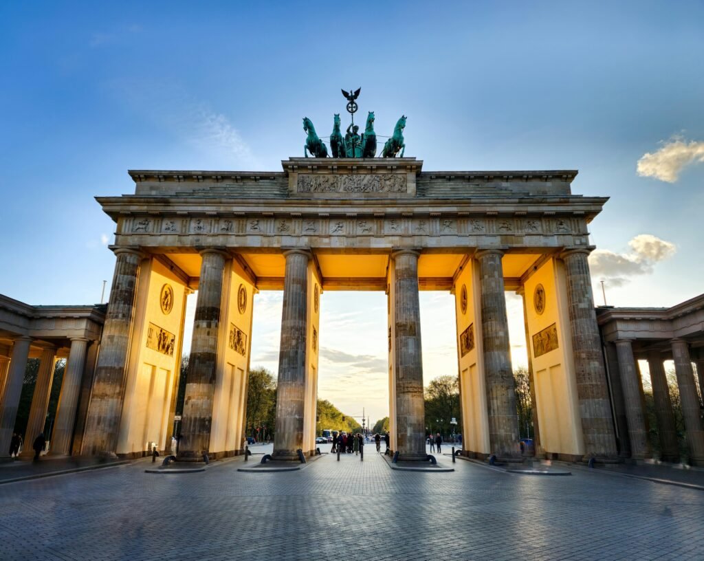 The iconic Brandenburg Gate in Berlin, captured during sunset with glowing light.