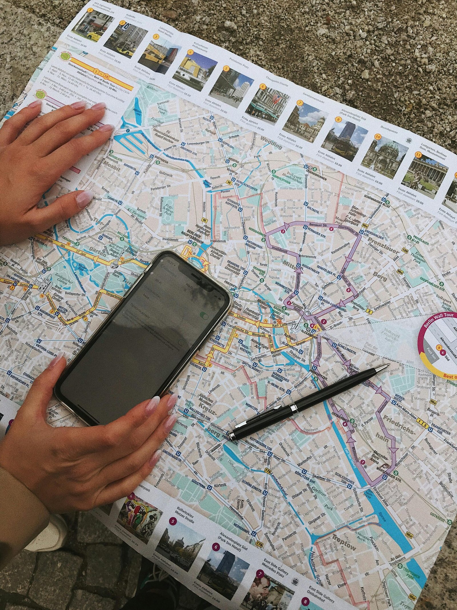 Hands interact with a Berlin map and smartphone, highlighting travel planning.